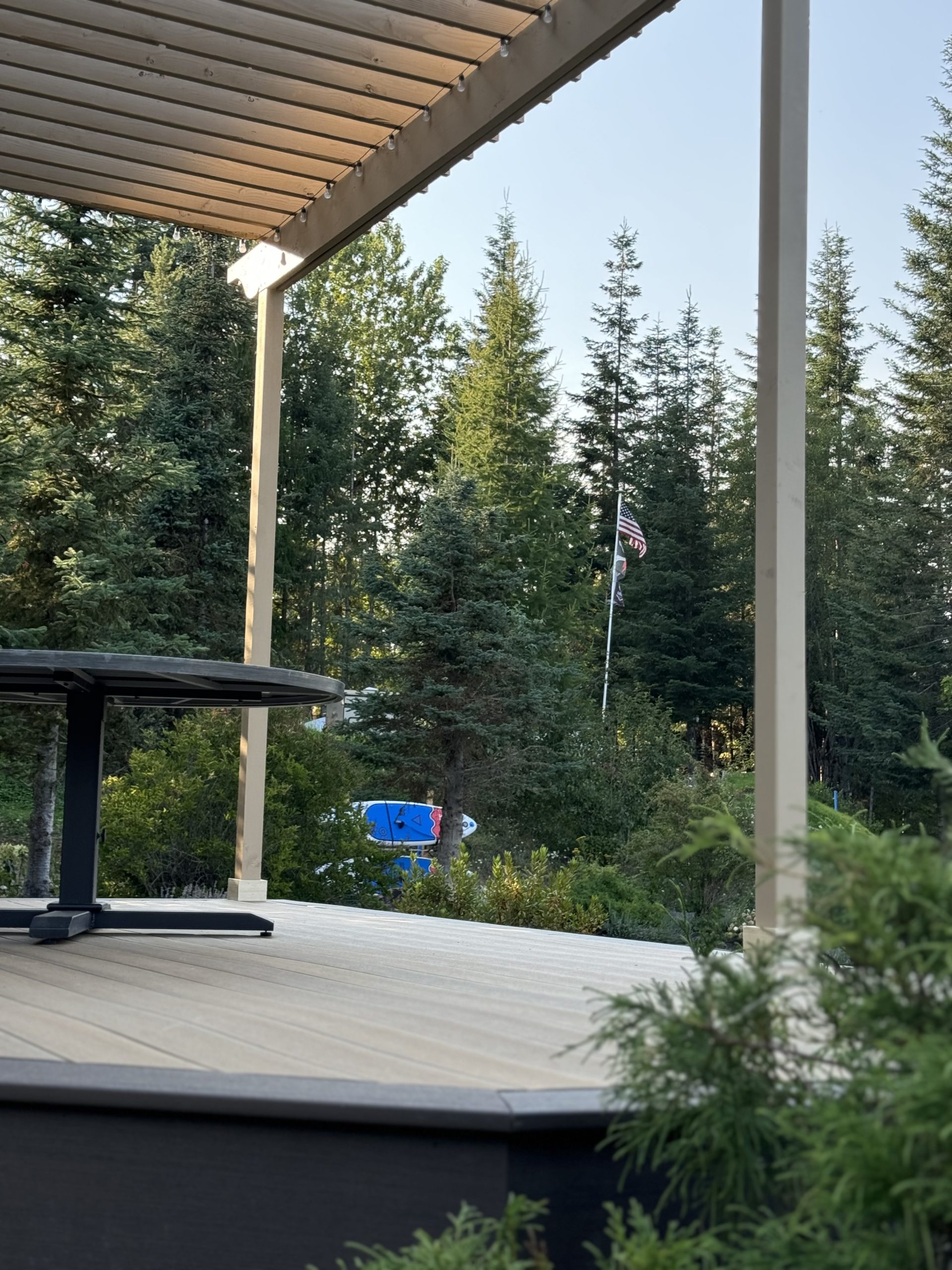 Back deck overlooking the forest and the american flag, with pergola above, located in sandpoint idaho.