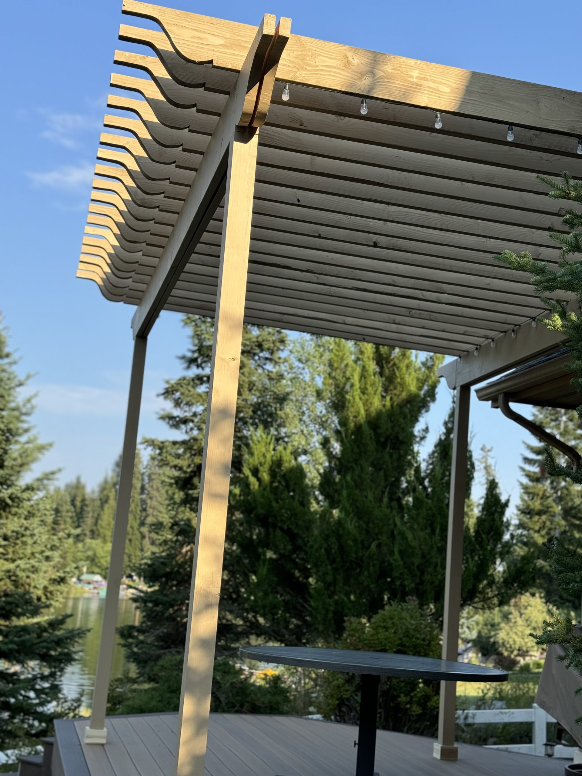 This is a wood pergola covering a back porch in sandpoint idaho, surrounded by trees.