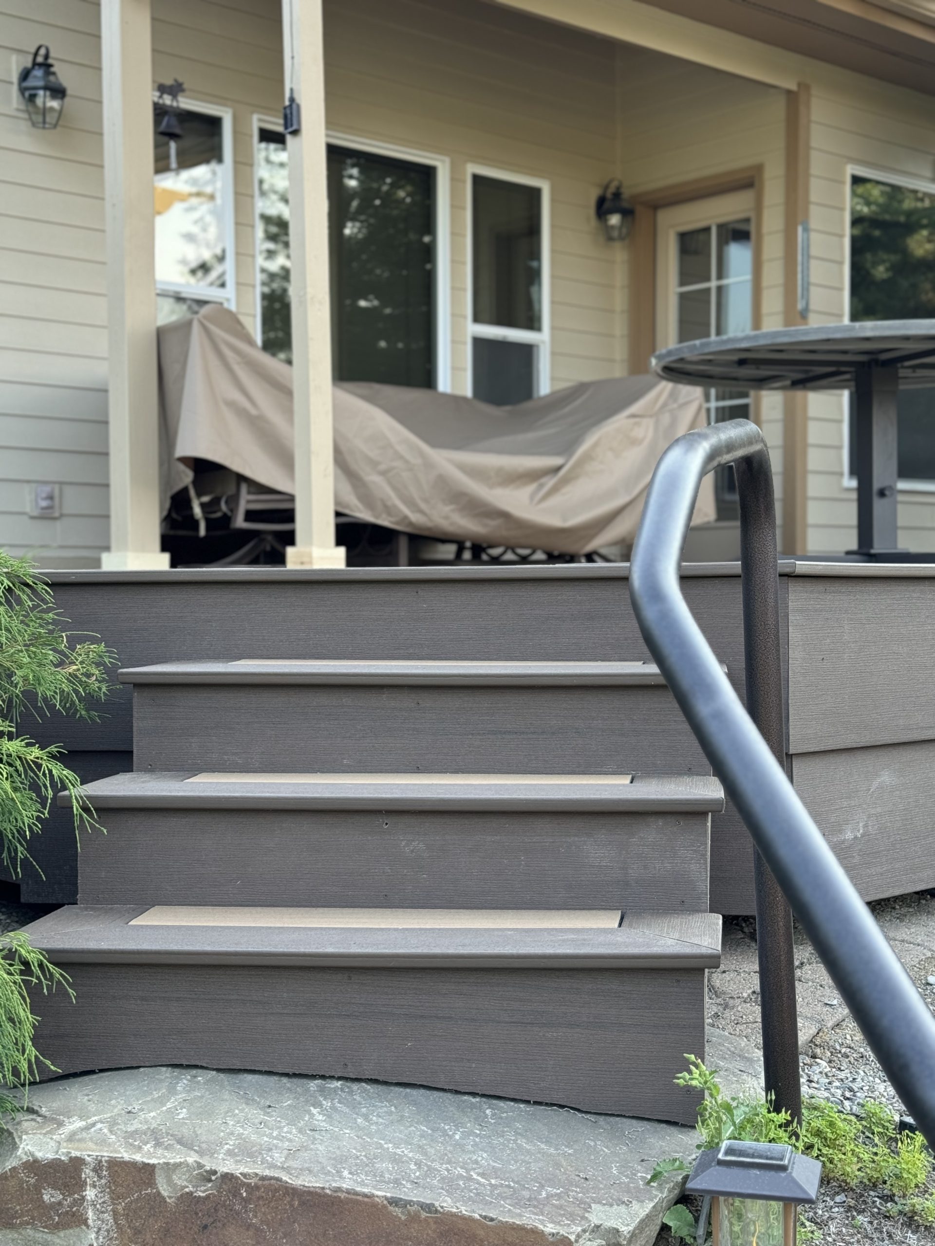 Back deck made with treks decking, with a railing, steps, and a table, in sandpoint idaho.